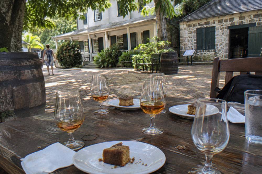 Guided walking group tasting rum cake and appetizers at a Nassau distillery courtyard table